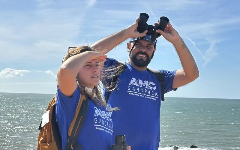 Guias da AMO com binóculo, olhando o mar