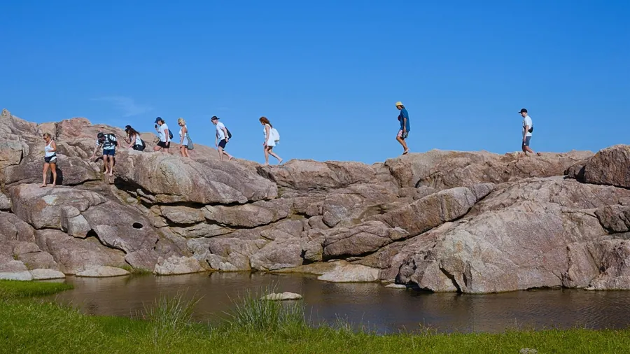 Grupo em trilha sobre as pedras, olhando o mar